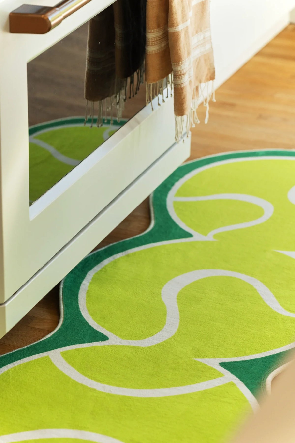 Close up of the green tennis runner beside the oven door, showing curved white court lines and rounded forms