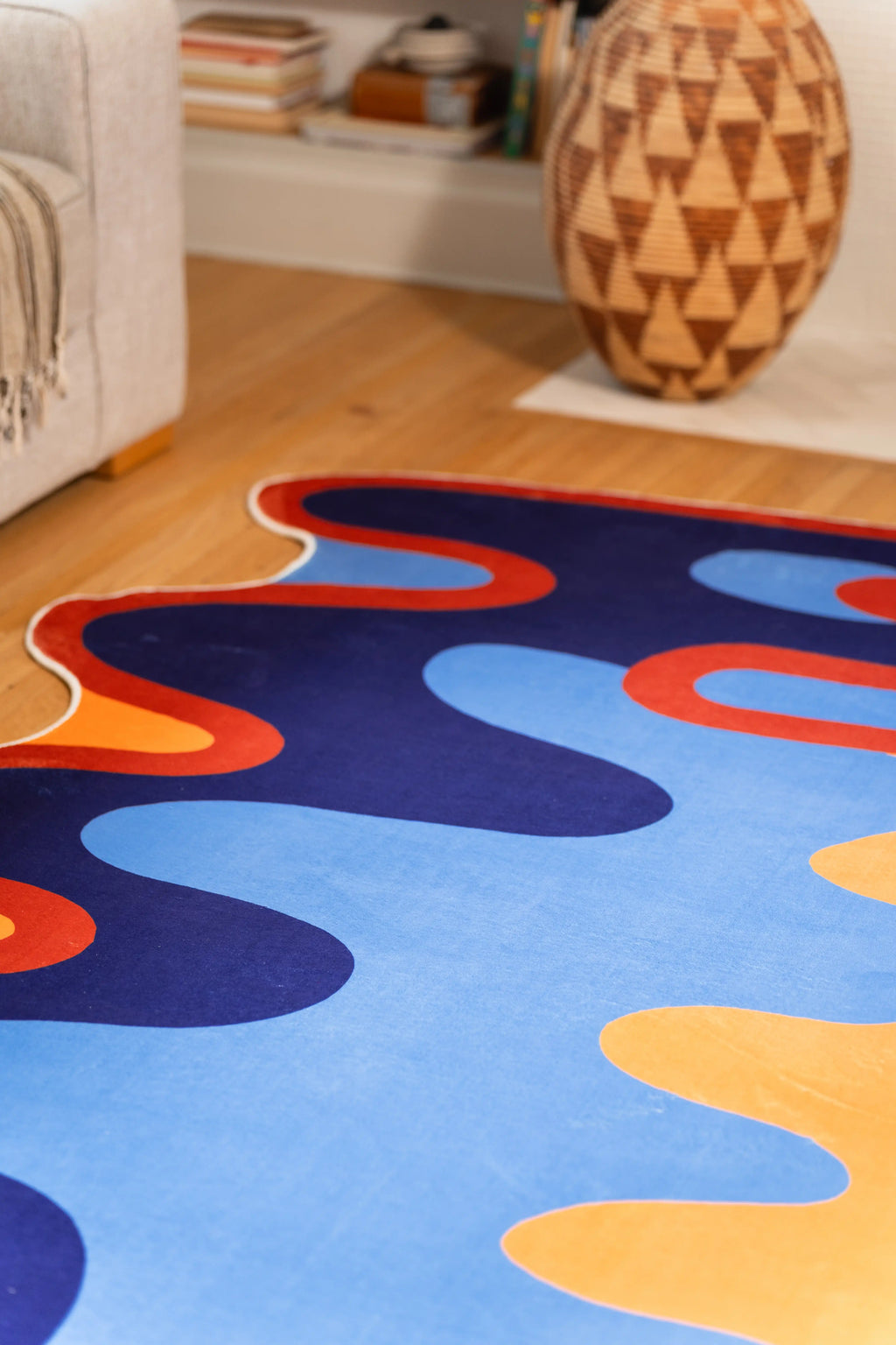 A close view isolates the navy center, pale blue pools, orange blocks, and rust border near a carved wooden vase.