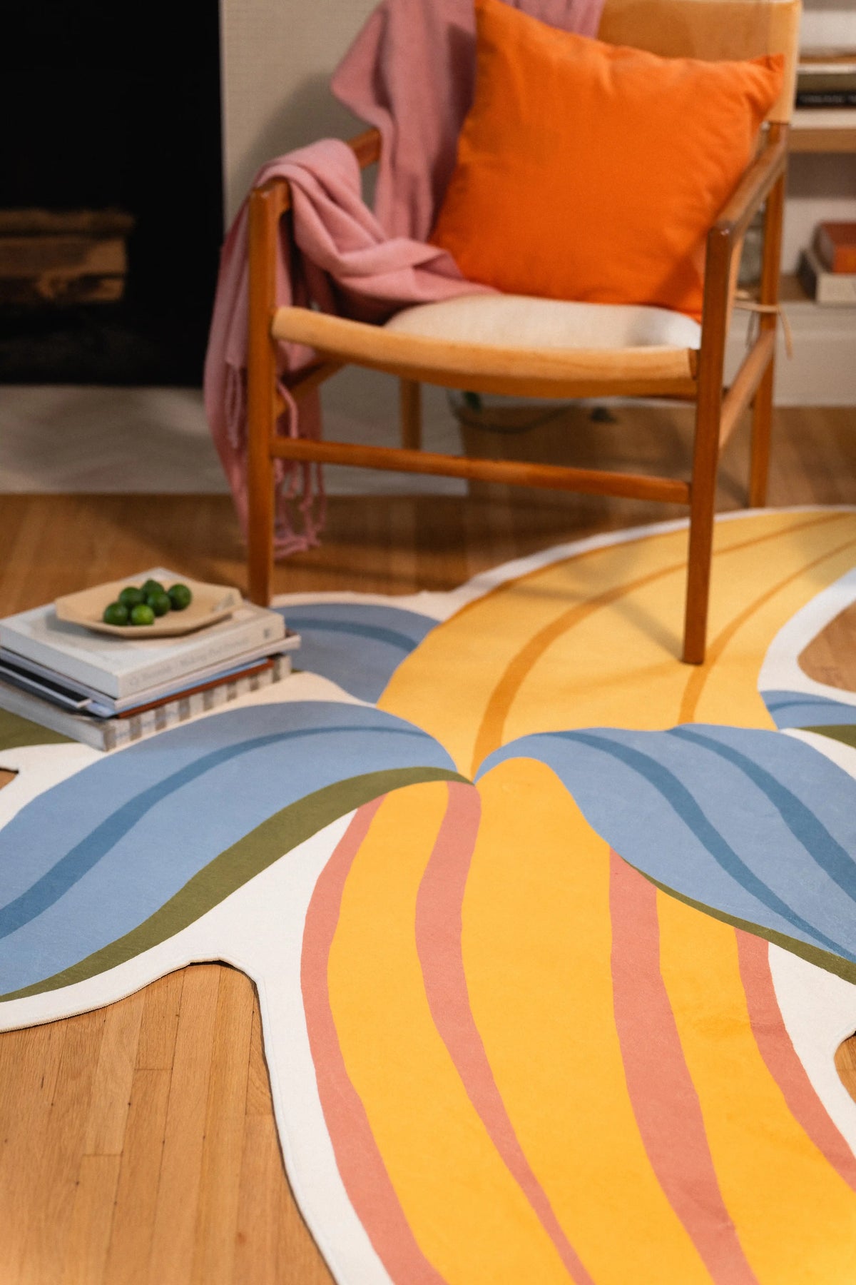 Pink-striped yellow banana fruit and blue peel sections beneath a wooden chair with an orange cushion.
