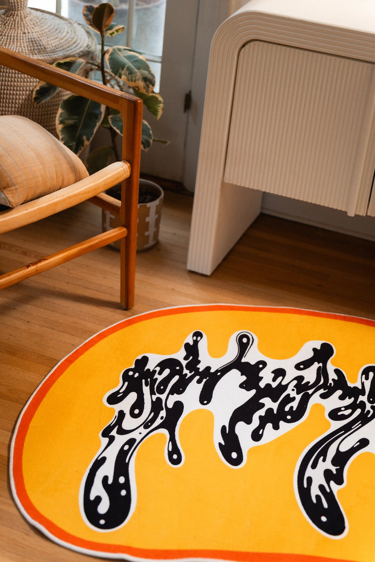 One rounded end of the rug frames a white pool filled with black brushlike swirls against the golden yellow ground.