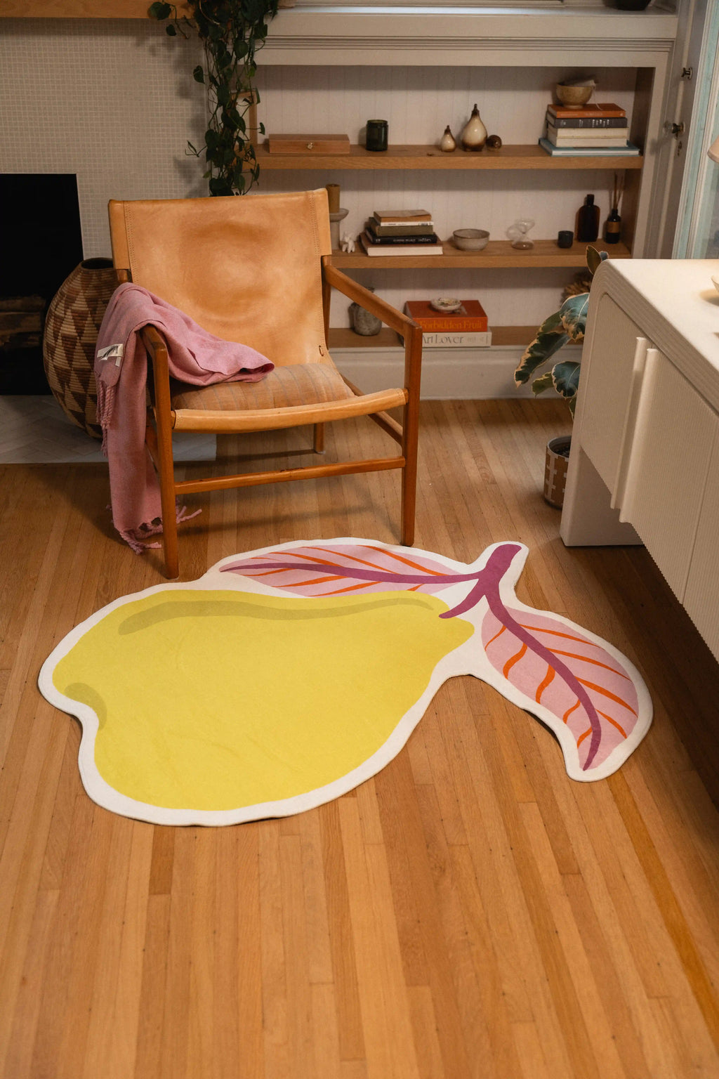 4' × 5' pear-shaped rug with yellow fruit and two pink leaves beside a wooden chair and white cabinet.