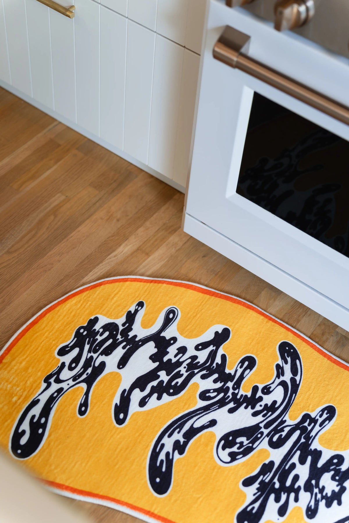 The white center opens between clusters of black strokes in this close kitchen view of the yellow rug.