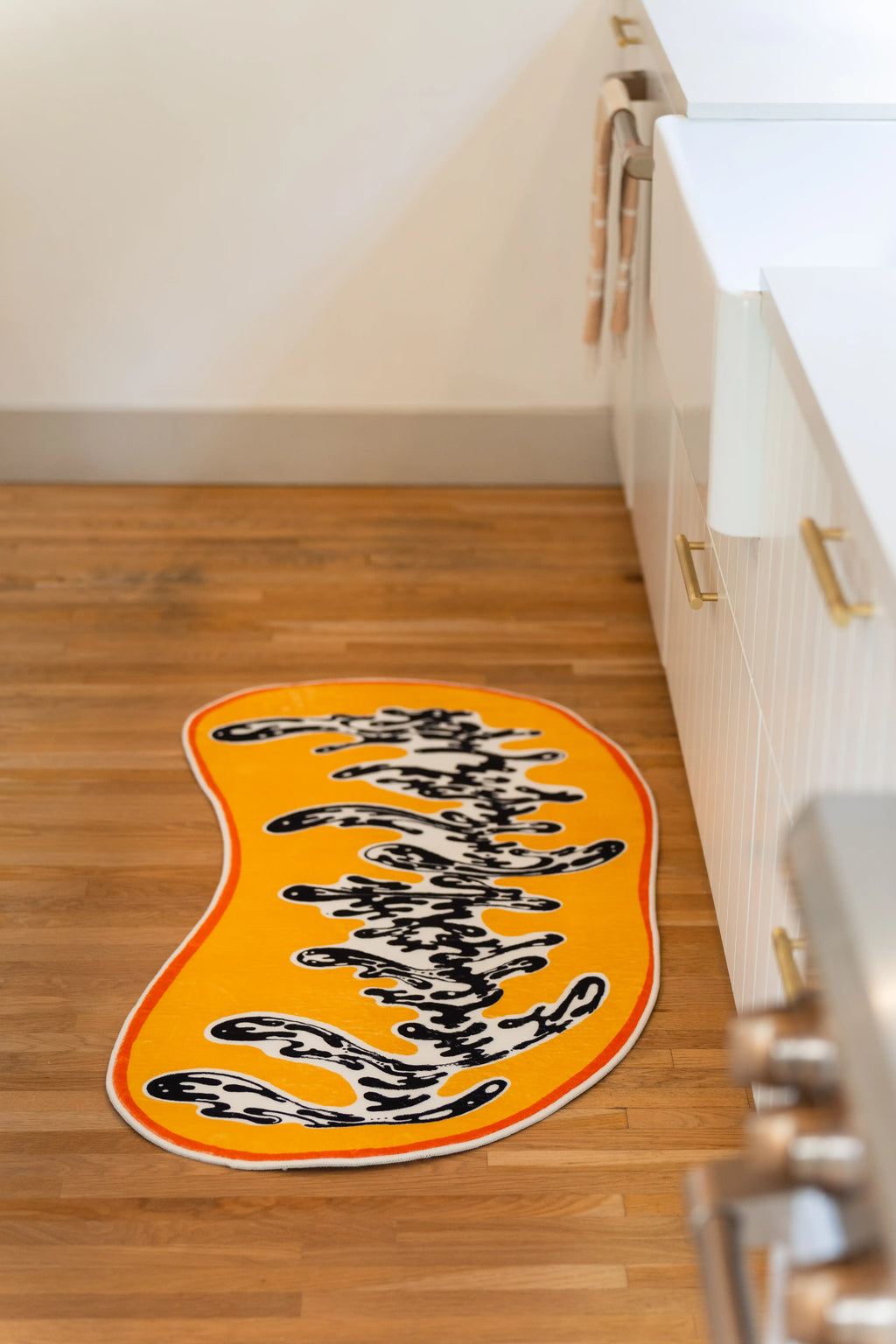 Seen lengthwise along the cabinets, the swirling black pattern travels down the center of the golden rug.