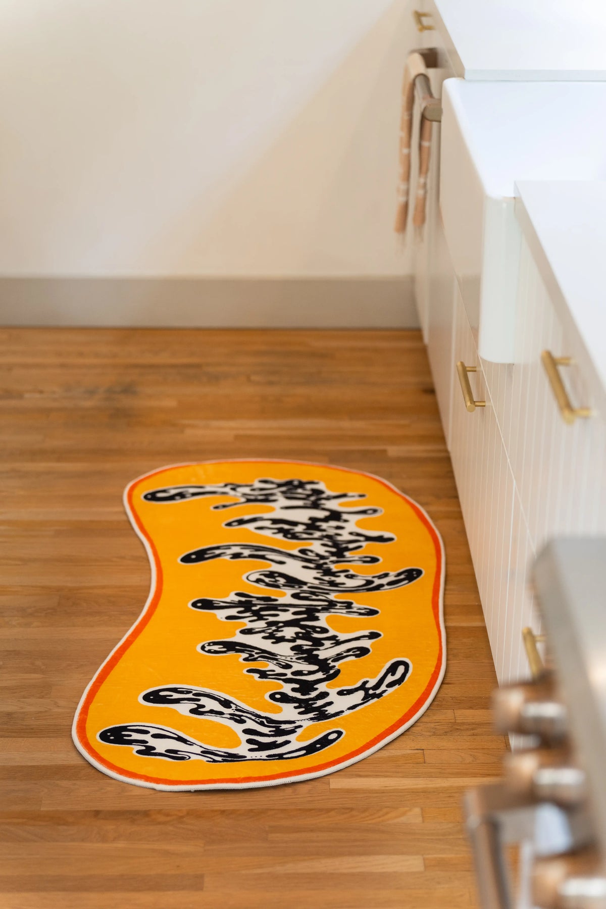 Seen lengthwise along the cabinets, the swirling black pattern travels down the center of the golden rug.