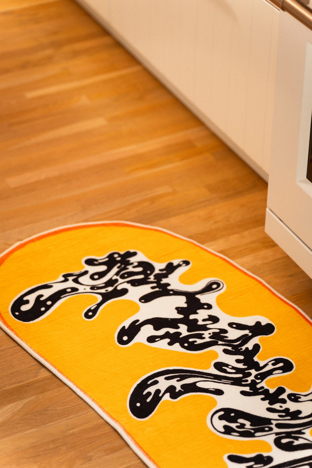 Close-up of the orange binding and black-and-white swirl at one curved end of the yellow rug.