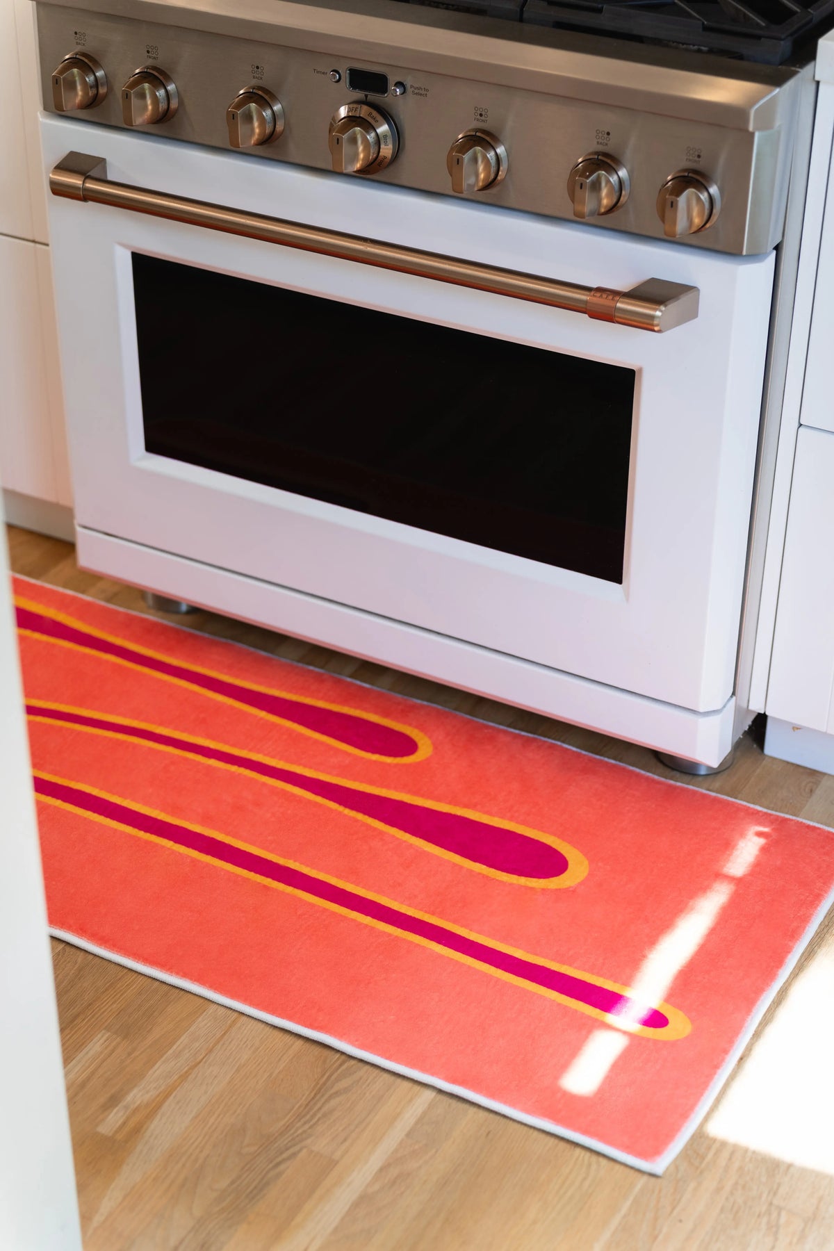 Close-up of the coral runner rug extending across the floor in front of a white kitchen range.