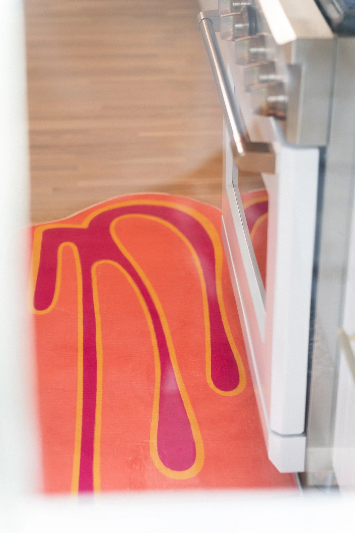 Top view of a coral orange runner with magenta and yellow lines beside a white kitchen range.