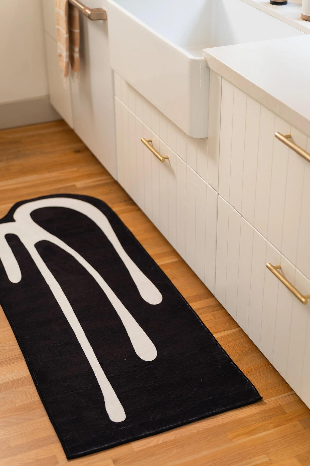2' × 5' black kitchen runner with white melting lines beside a farmhouse sink and white cabinets.
