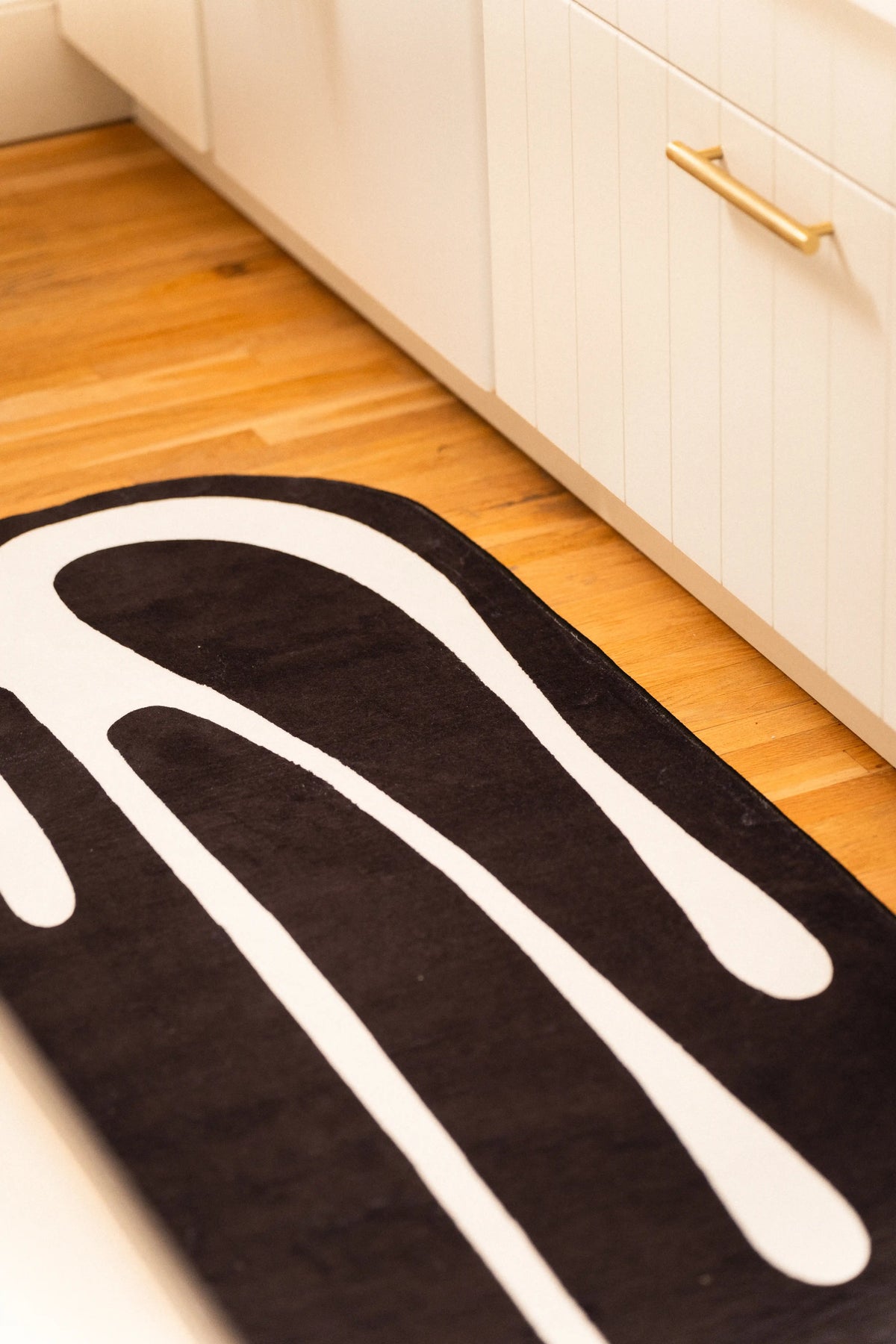 Close-up of long white drip lines across a black runner beside white kitchen cabinetry.