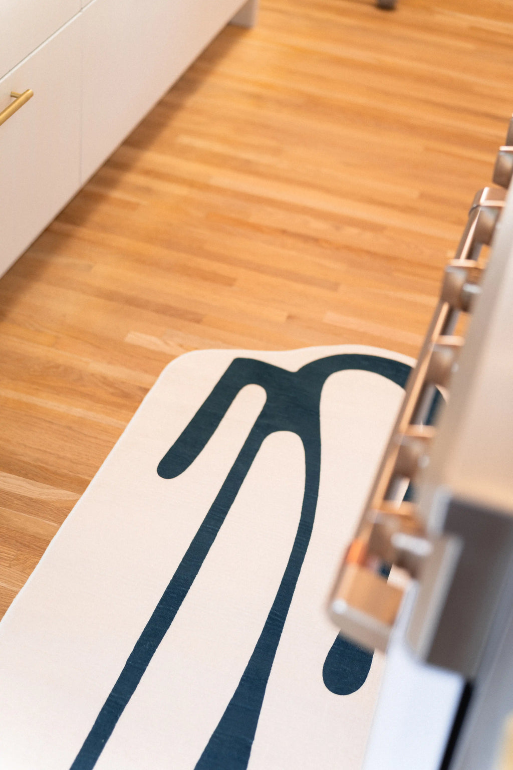 Top view of a narrow beige runner with long green lines beside a white oven.