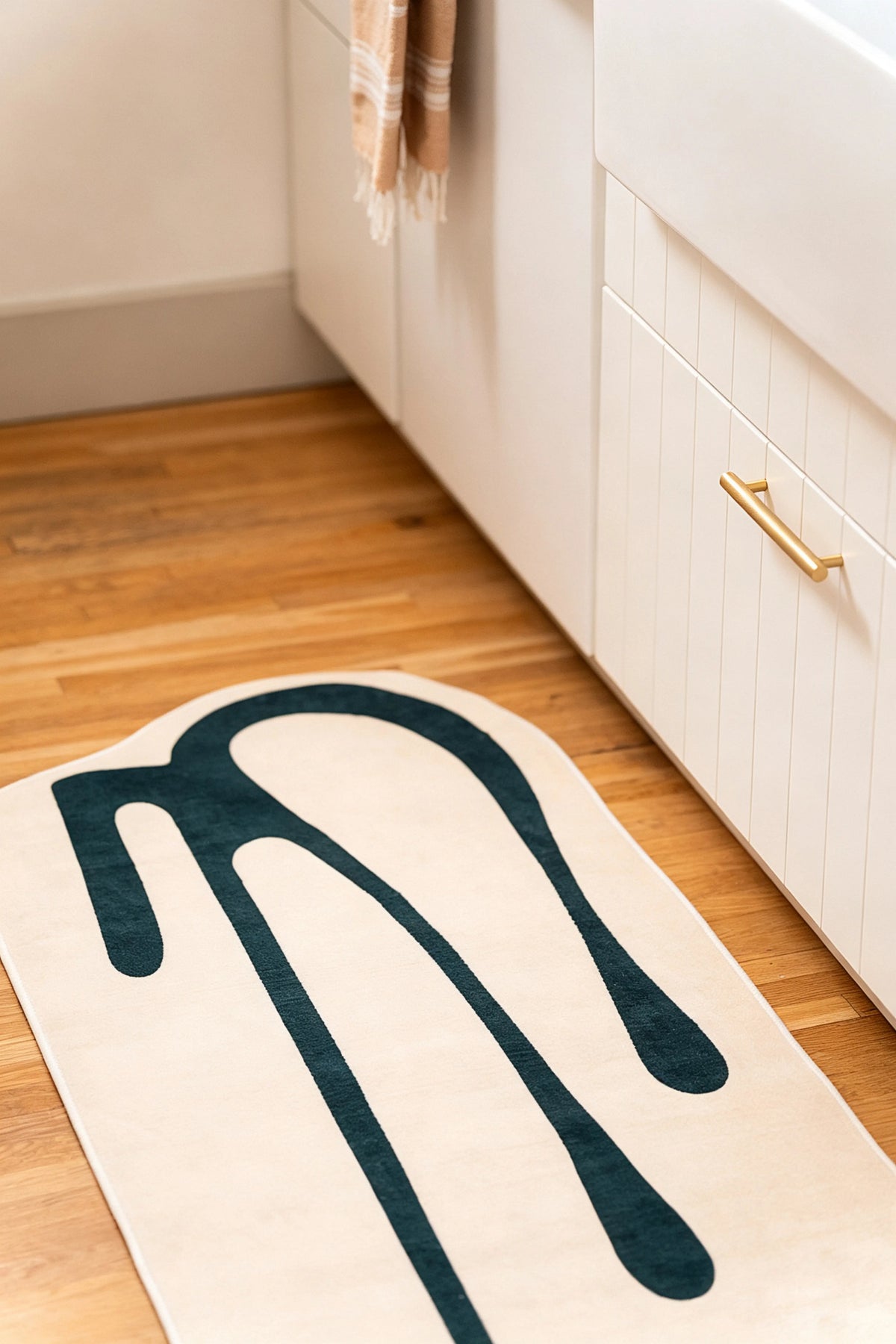 Front view of a beige and green runner laid beside white lower kitchen cabinets.