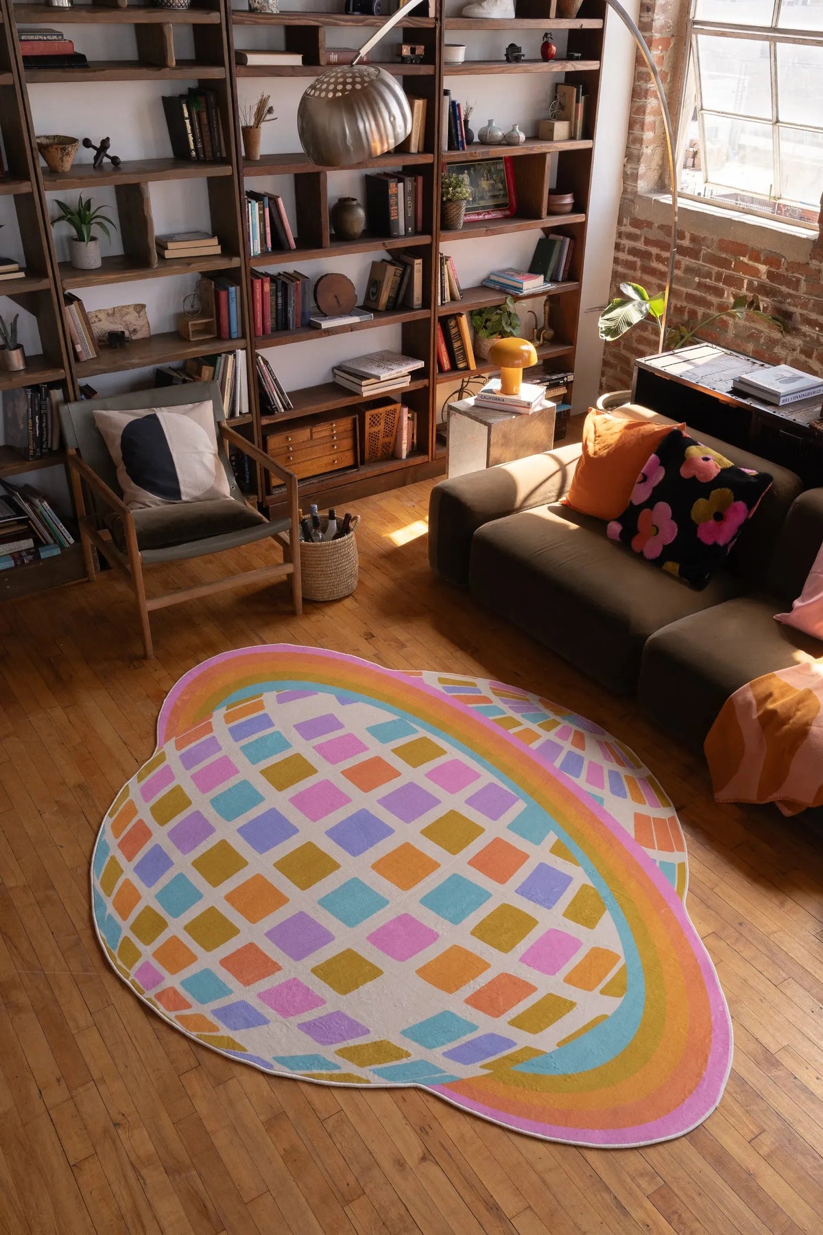 Colorful Disco Planet Checkered Rug by Darra Sargnt centered on wood floor, placed in front of a dark sofa with warm cushions and throw