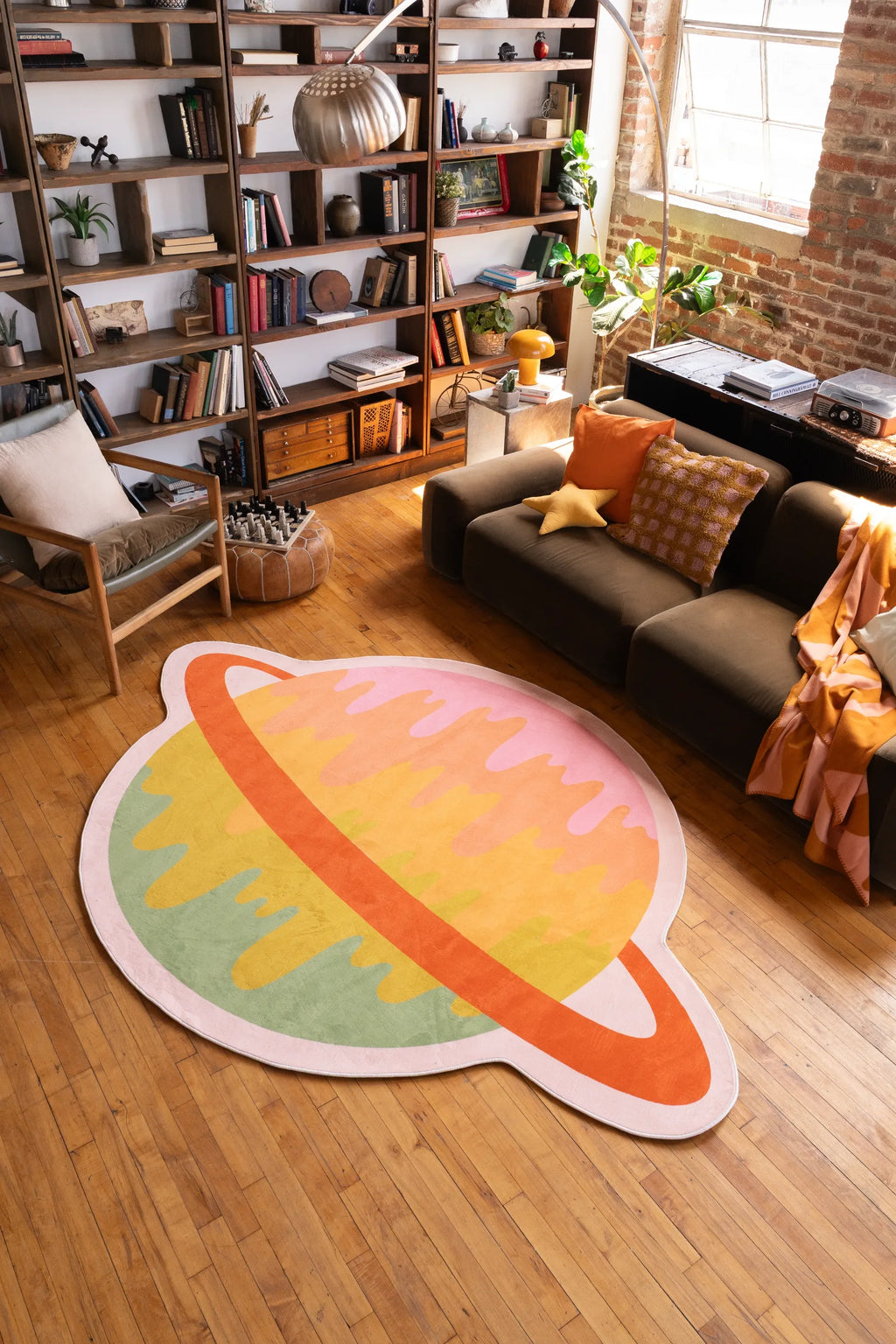 Melting Planet Colorful Rug by Darra Sargnt in a cozy living room with bookshelf, sofa, and wood floor.
