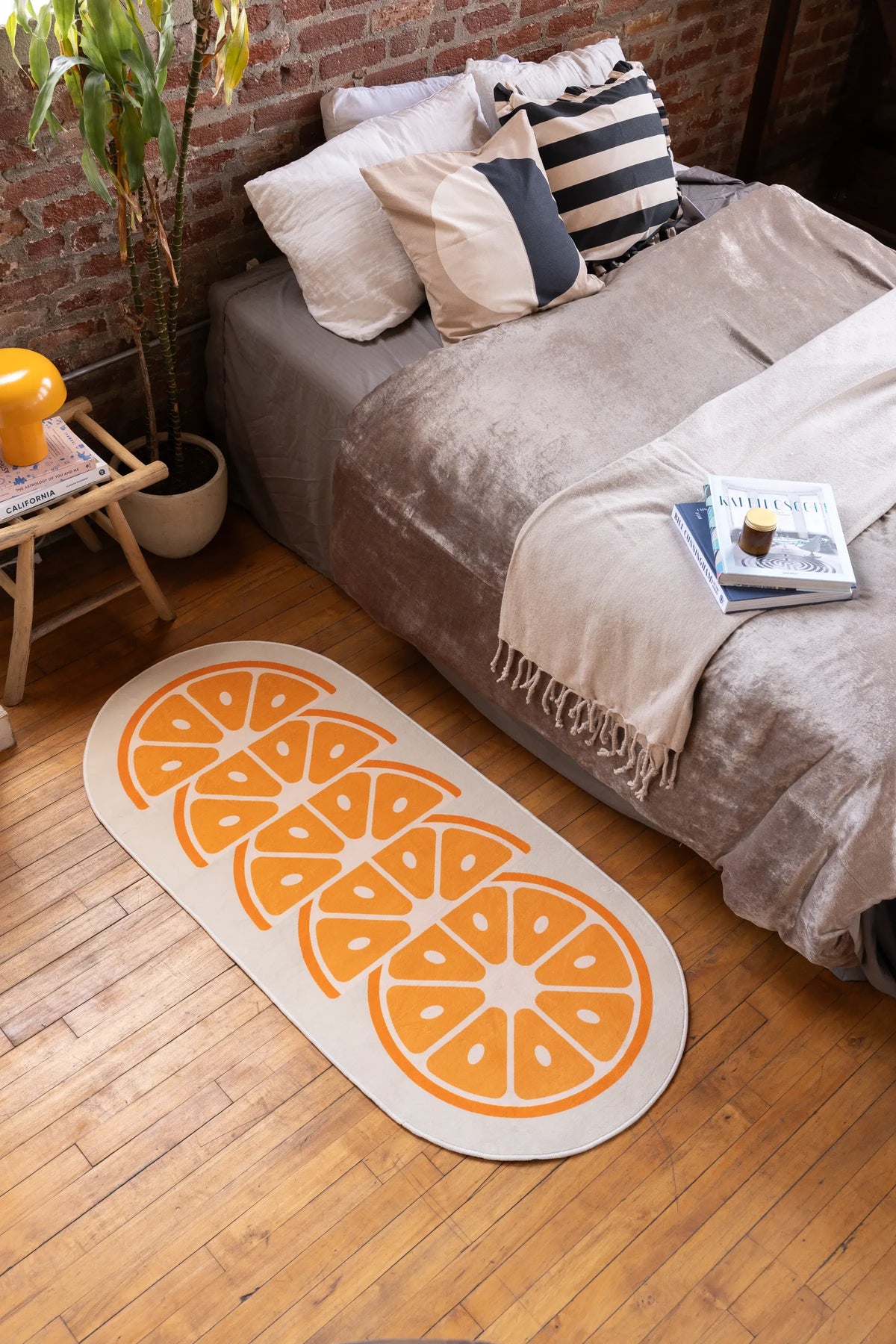 Bright bedroom with White Modern Orange Rug placed on wooden floor next to bed with stacked pillows and beige blanket