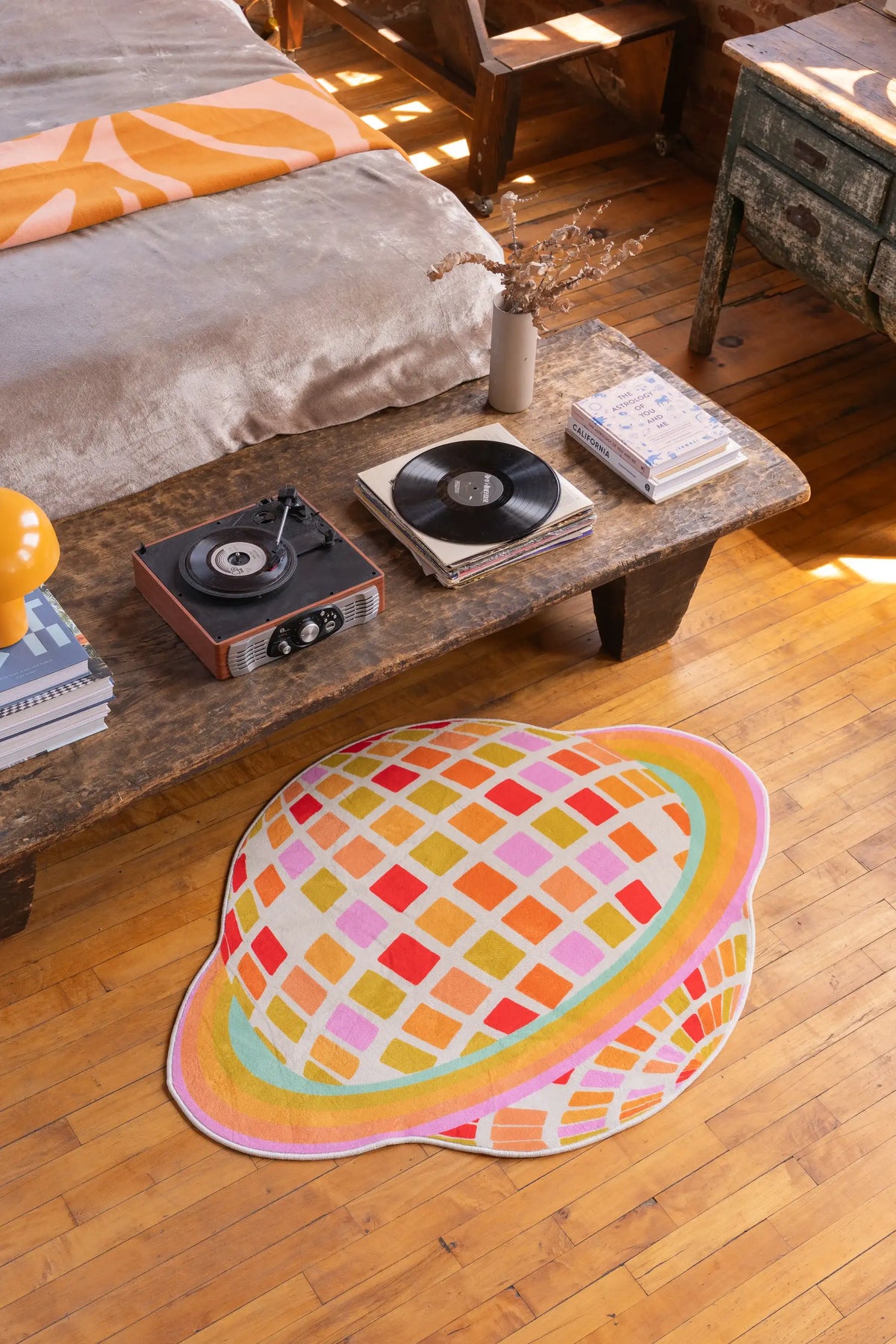 Orange planet checkered rug set beside a rustic wood table and couch, adding bold color to the open floor space