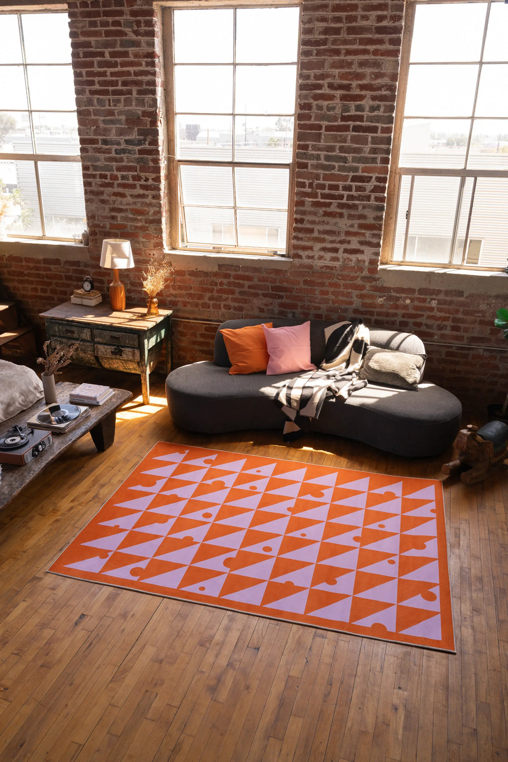 Living room with a geometric patterned rug, sofa, and brick wall.