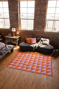 Living room with a geometric patterned rug, sofa, and brick wall.