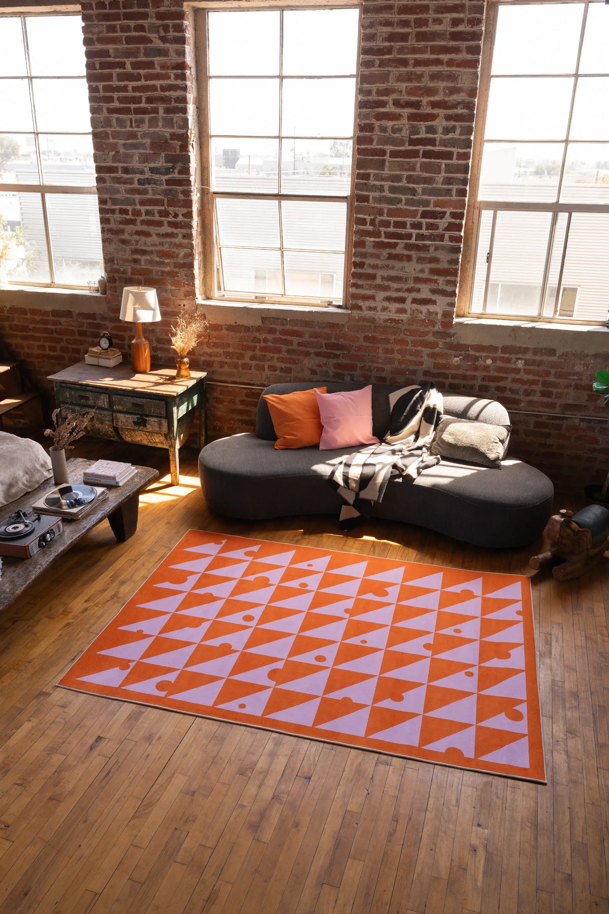 Living room with a geometric patterned rug, sofa, and brick wall.