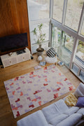 Pink pastel mosaic rug laid on wood floor between a white sofa and chair in the living room.