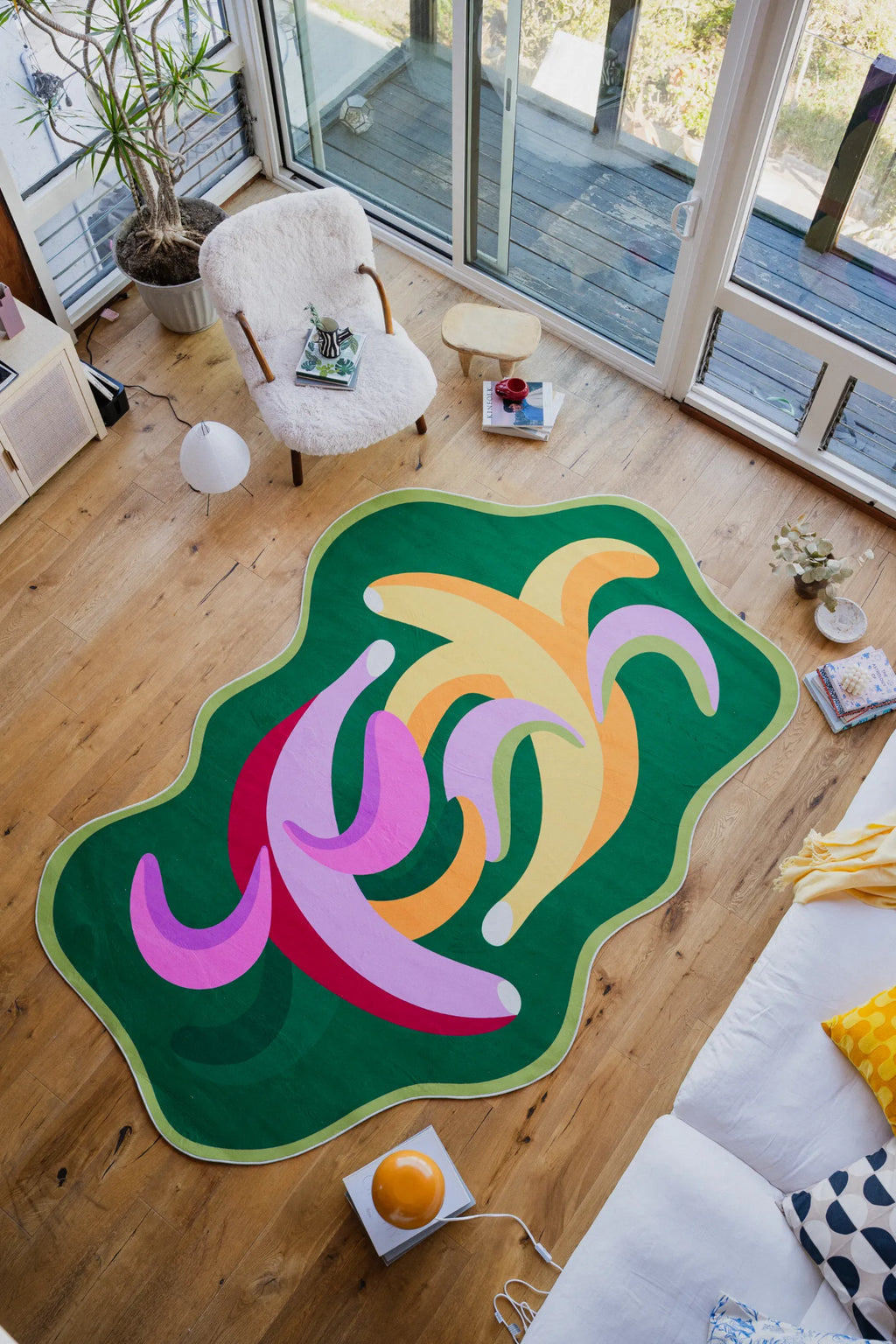 Funky bananas rug in a bright living room with large windows, surrounded by cozy furniture and sunlight.