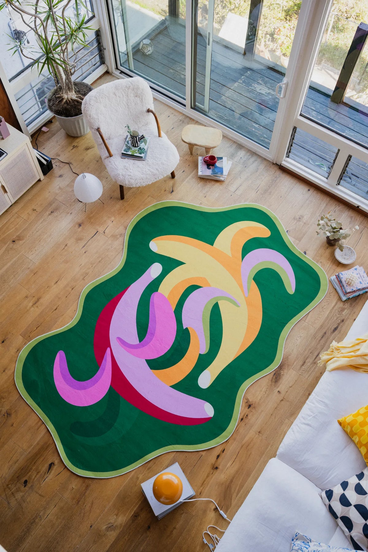 Funky bananas rug in a bright living room with large windows, surrounded by cozy furniture and sunlight.