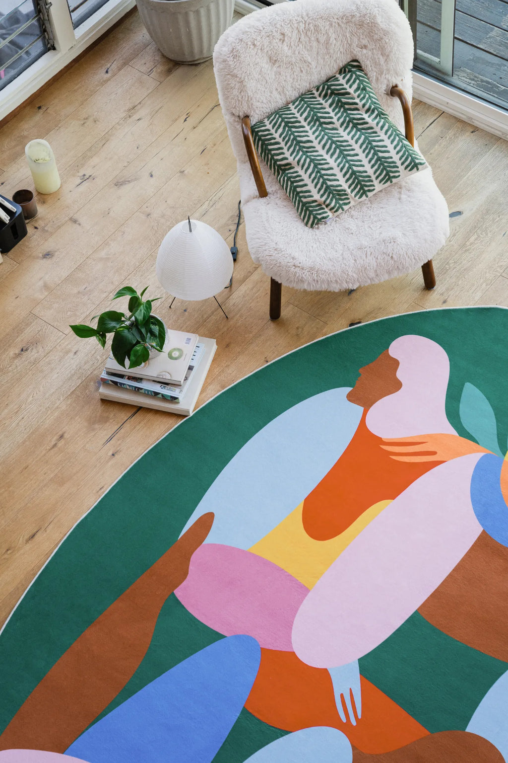 Oval fruitvine green rug partially shown near a boucle chair with green leaf cushion in a bright corner.