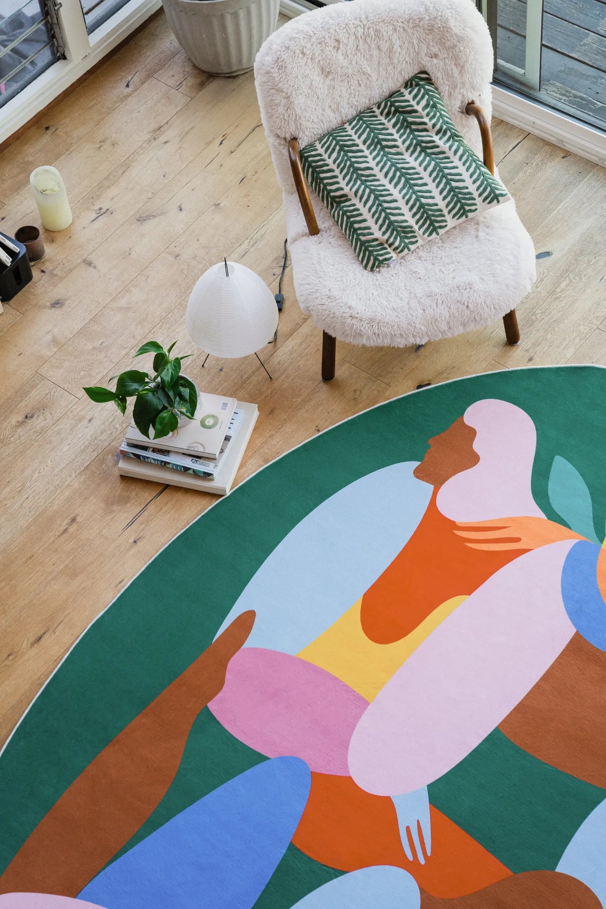 Oval fruitvine green rug partially shown near a boucle chair with green leaf cushion in a bright corner.