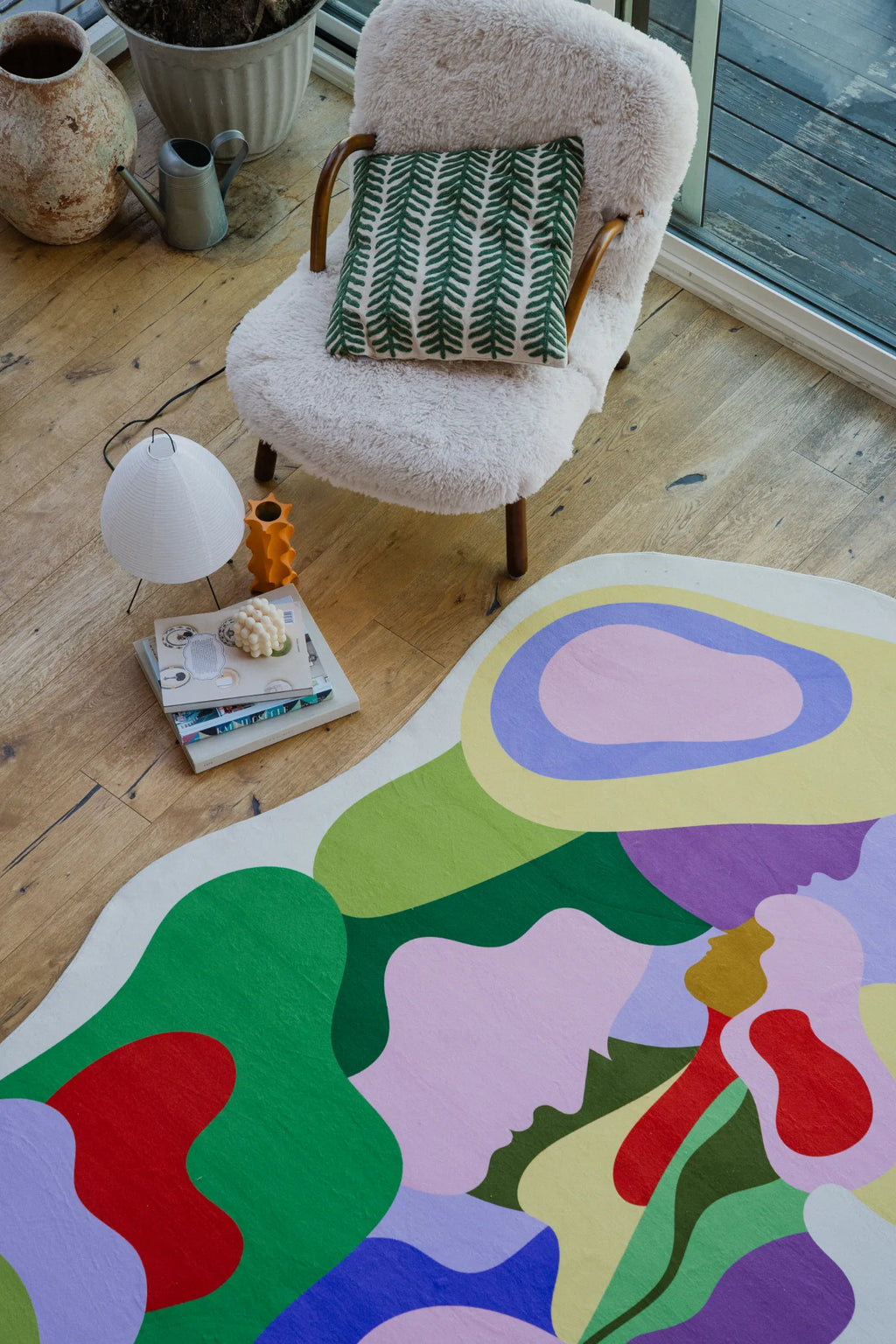 Corner of the living room showing the pastel Bloomland Unity rug next to a boucle chair with a green leaf pillow