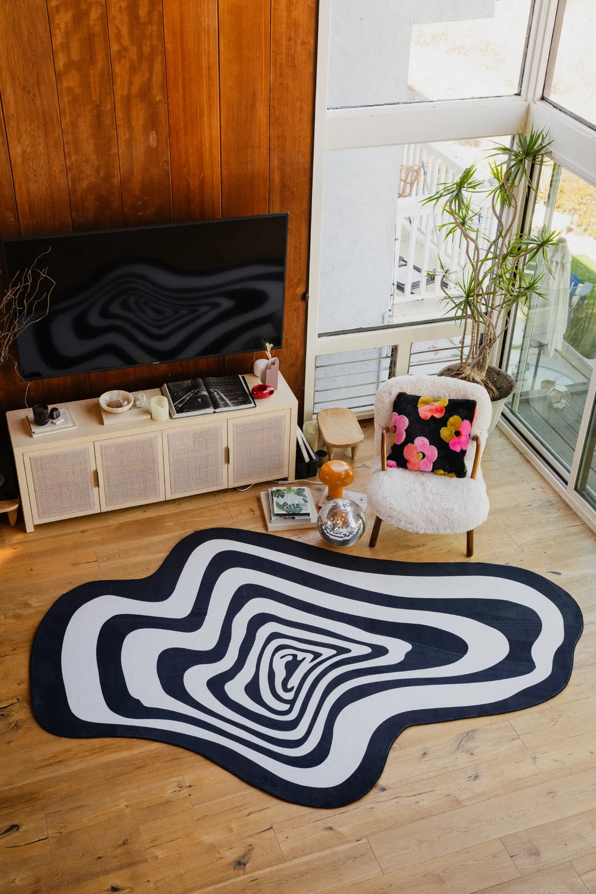 Living room scene featuring the black and white vertigo rug near a TV setup with wooden floors and modern decor.