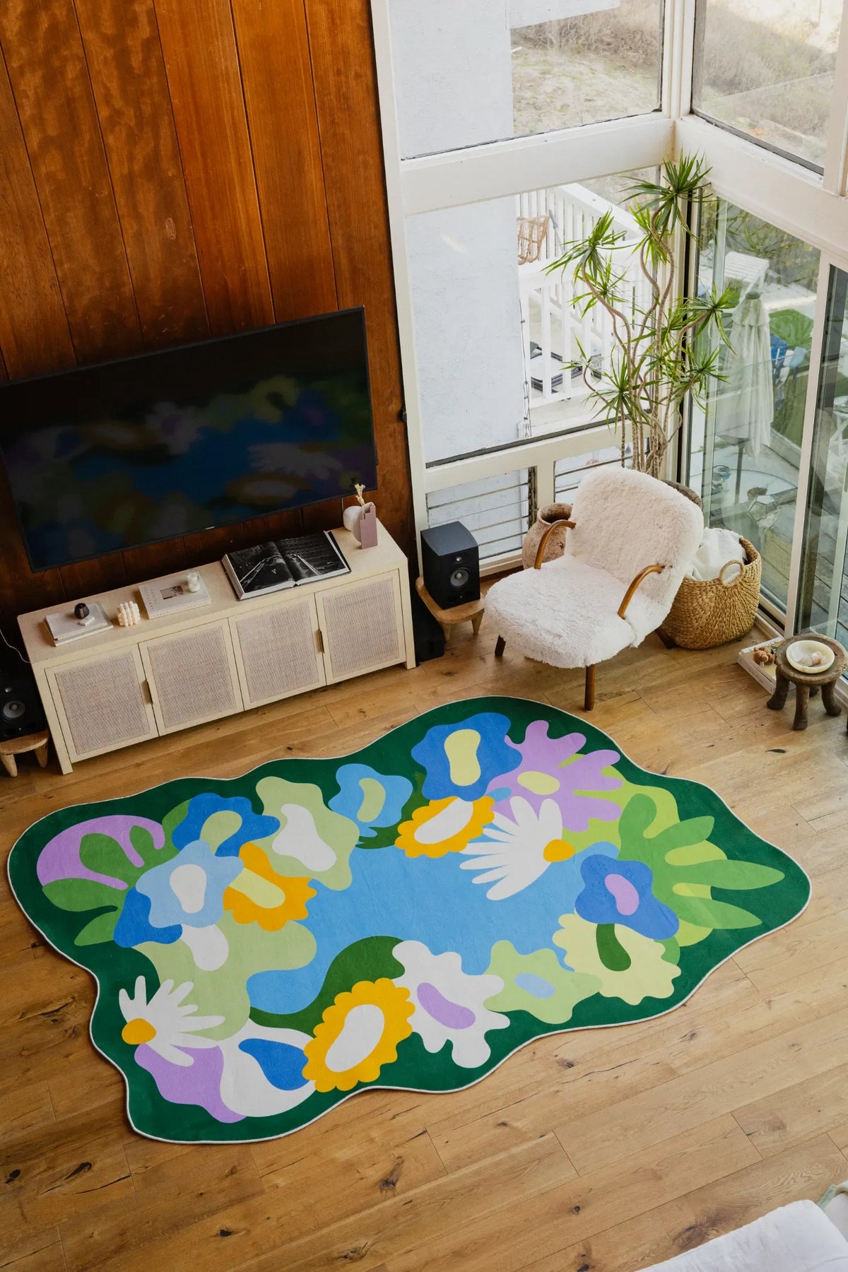 Floral rug with colorful blooms centered in a spacious living room near glass doors and a fuzzy armchair.
