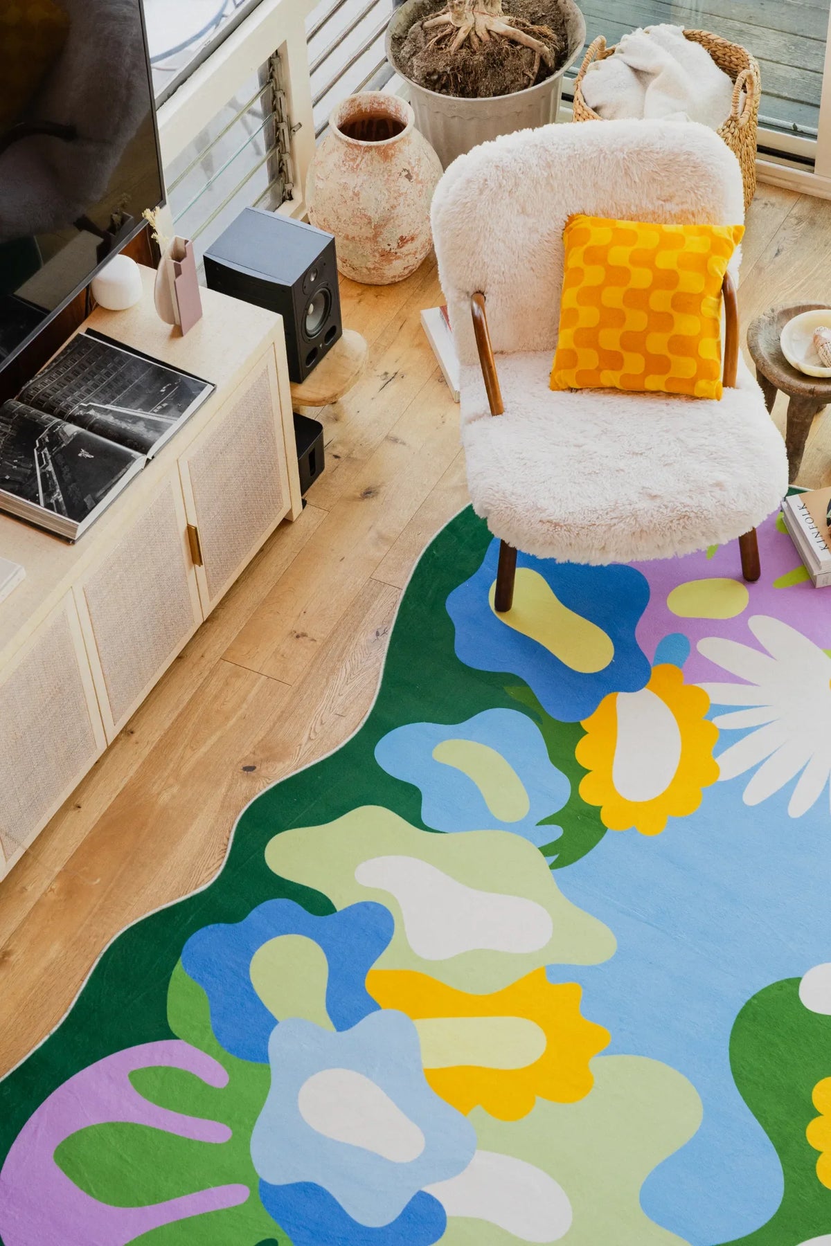 Floral rug with yellow and white blooms placed beside a fuzzy chair in a bright living room corner.