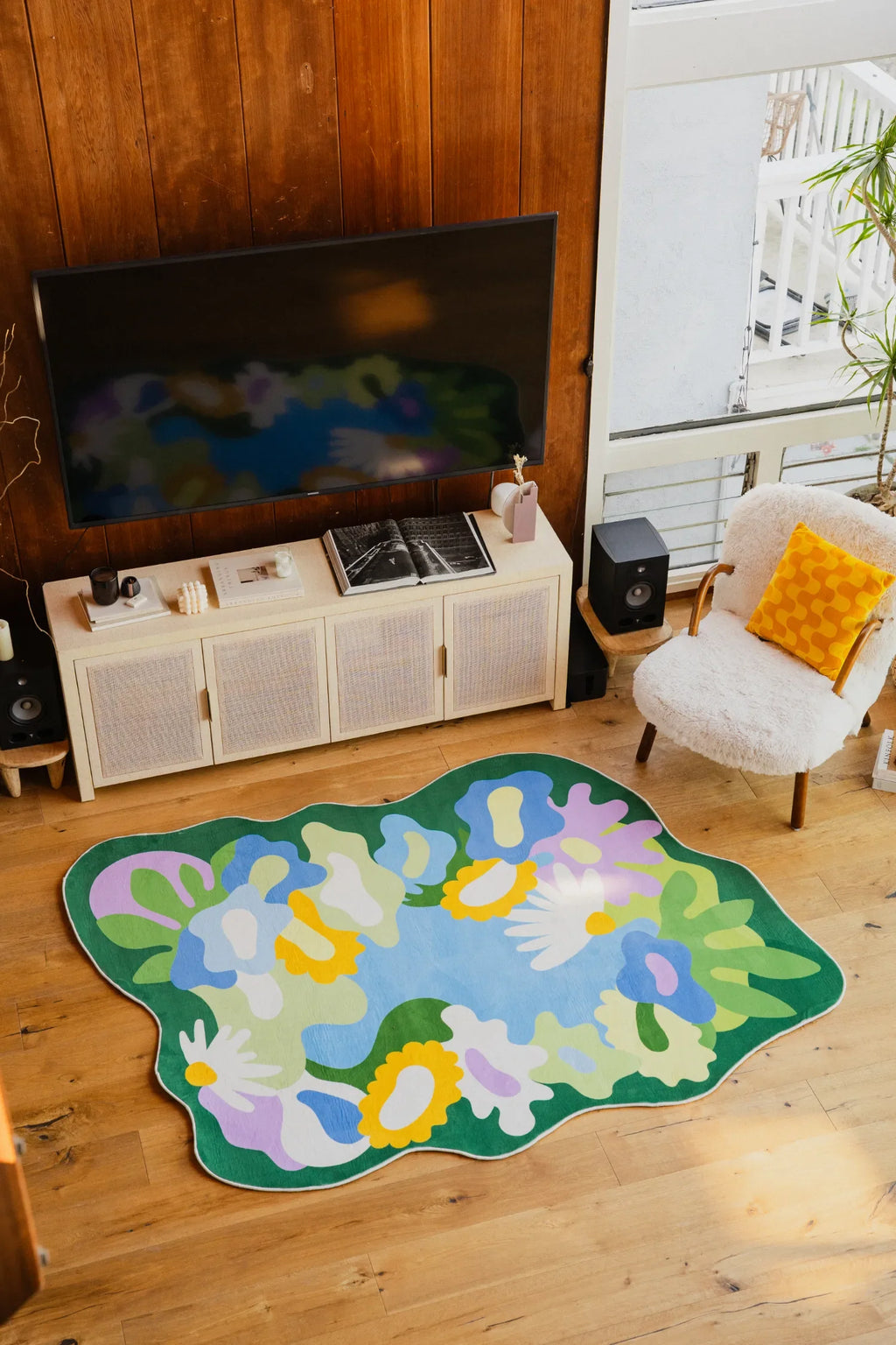 Irregular Botanical Garden Floral Rug by Maggie Stephenson placed in a cozy living room corner near a fuzzy chair and TV stand.