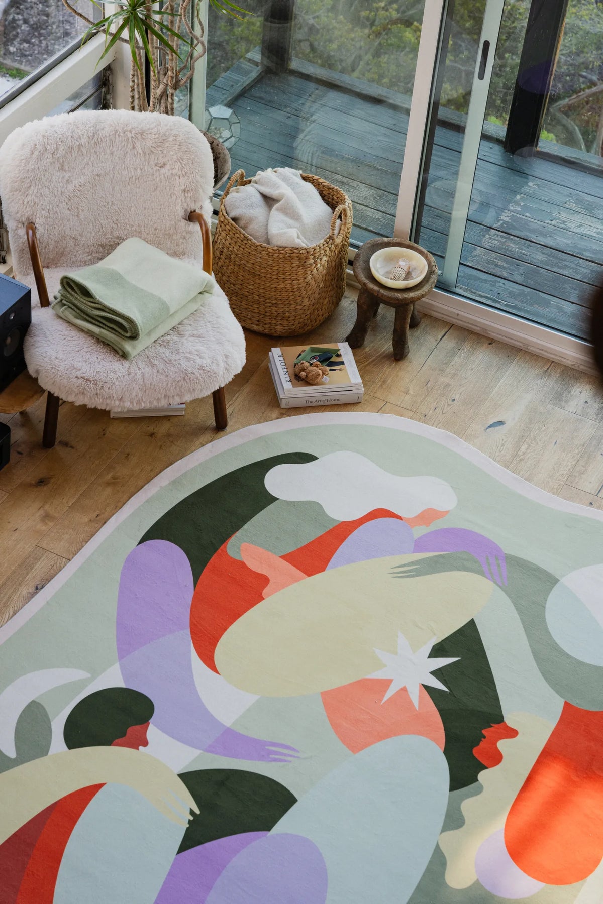 Close-up of the rug’s abstract pastel pattern beside a boucle chair and woven basket in a cozy corner.
