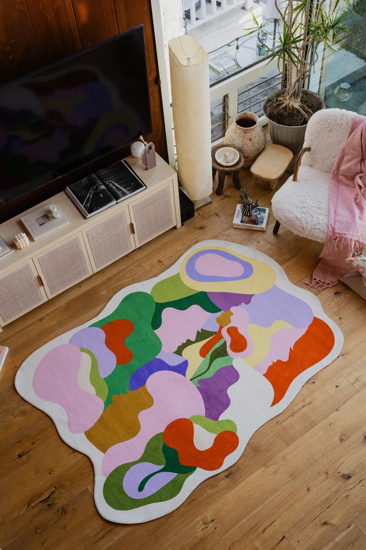 Detail of the Bloomland Unity pastel rug near a boucle chair, green pillow, and decorative lamp.
