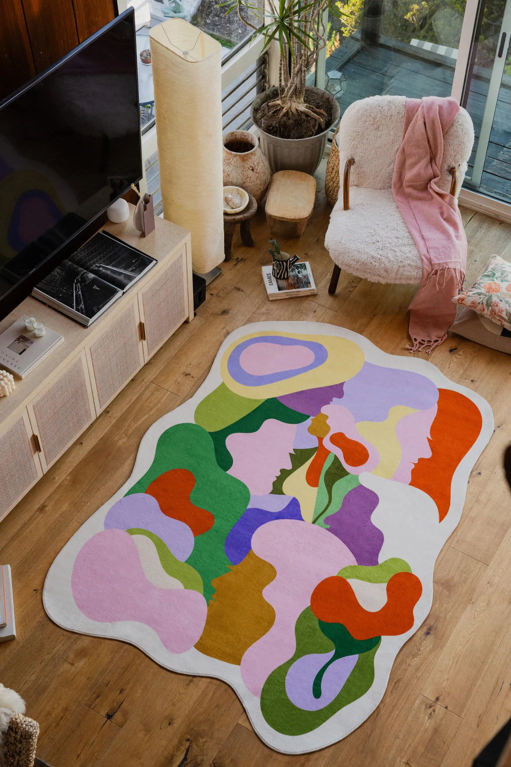 Bloomland Unity pastel rug in a cozy living room with pottery, plants, and a boucle chair with a pink scarf.