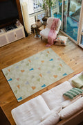 Neutral pastel rug placed between sofa and lounge chair on wood floor, a soft modern area rug touch.