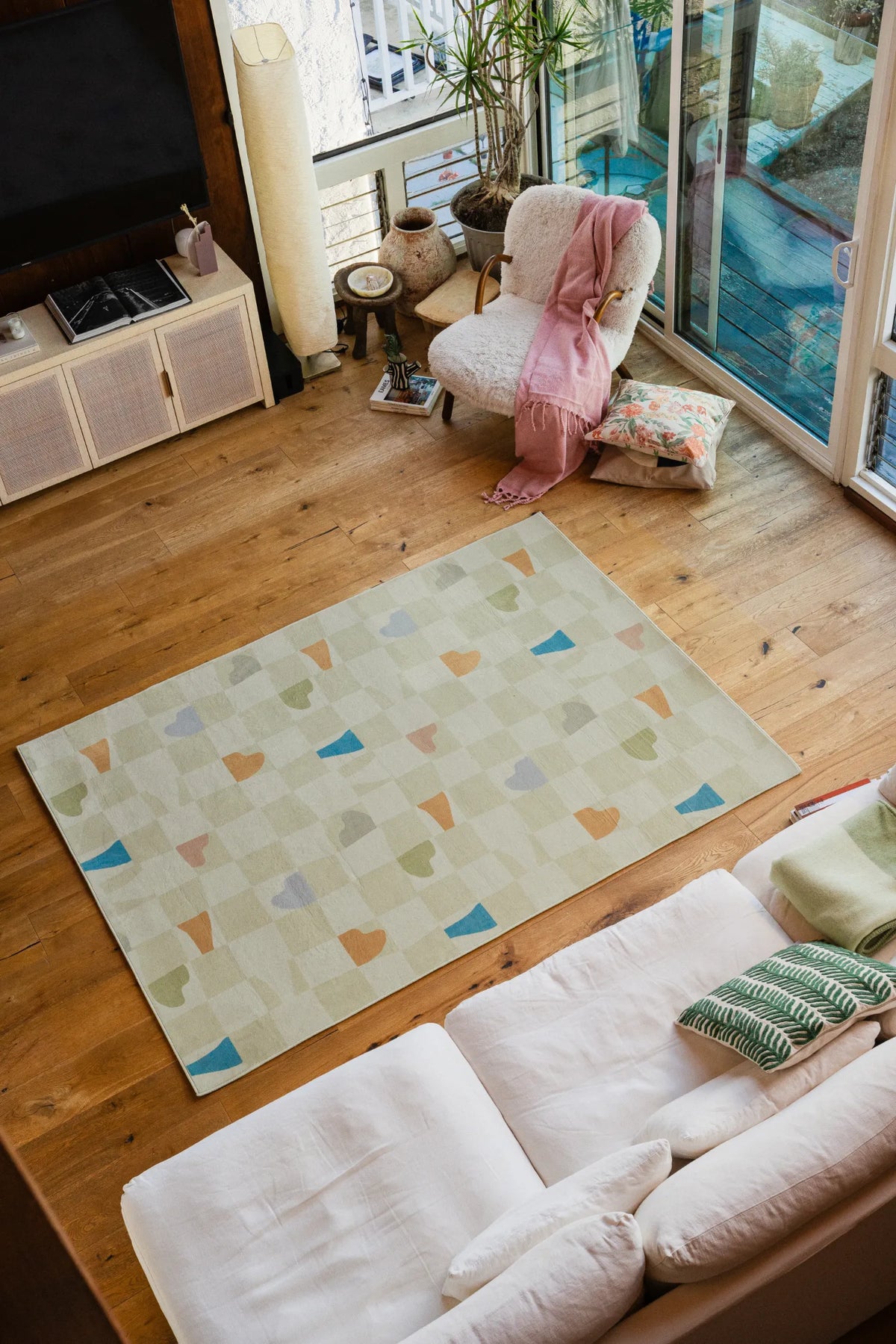 Neutral pastel rug placed between sofa and lounge chair on wood floor, a soft modern area rug touch.