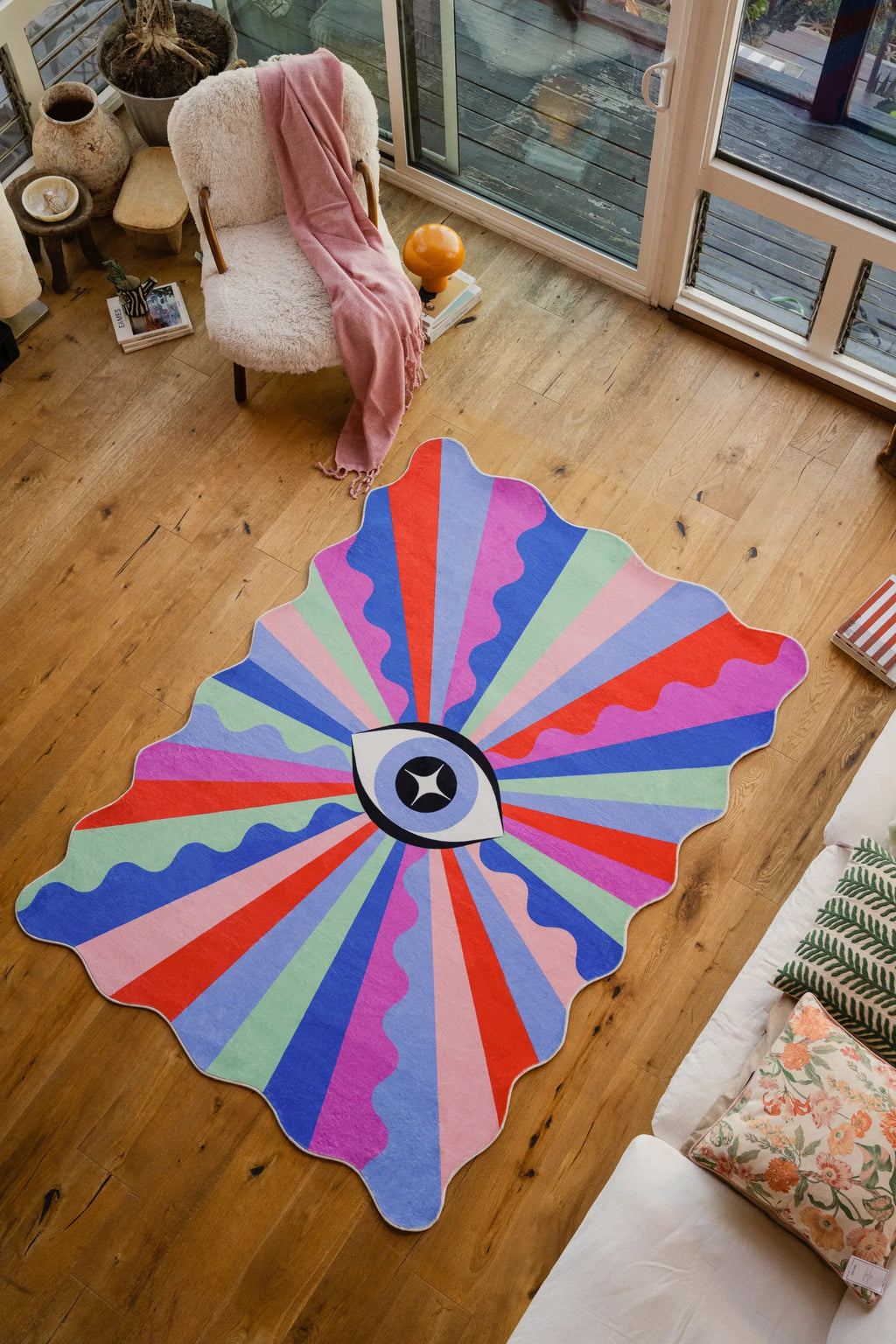 Colorful Lazer Rays Eye Rug laid out in a bright living room, its bold pattern grounding the space on wood floor.