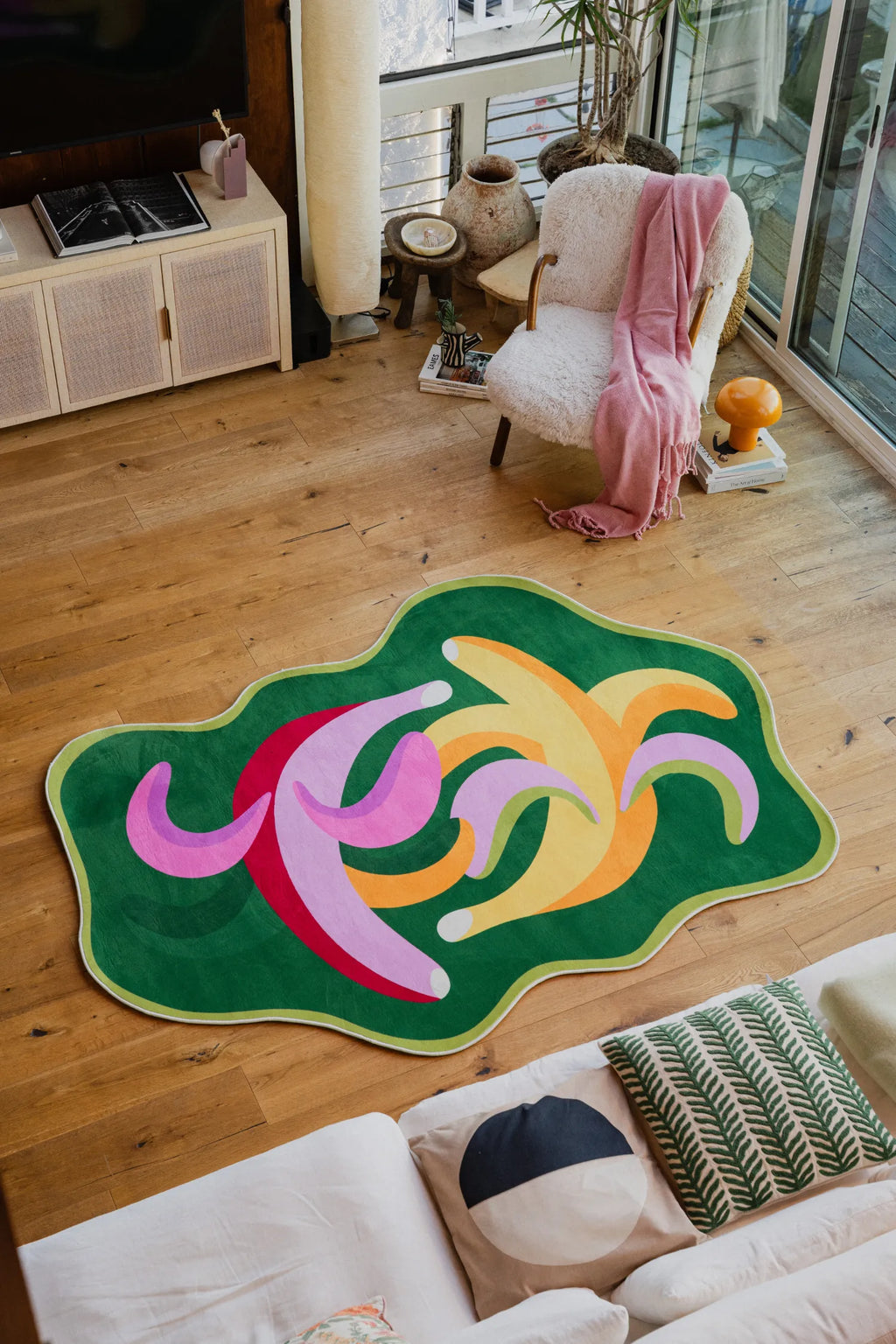 unky Dancing Bananas Rug by Maggie Stephenson styled in a cozy living room with a boucle chair, side tables, and a throw blanket.