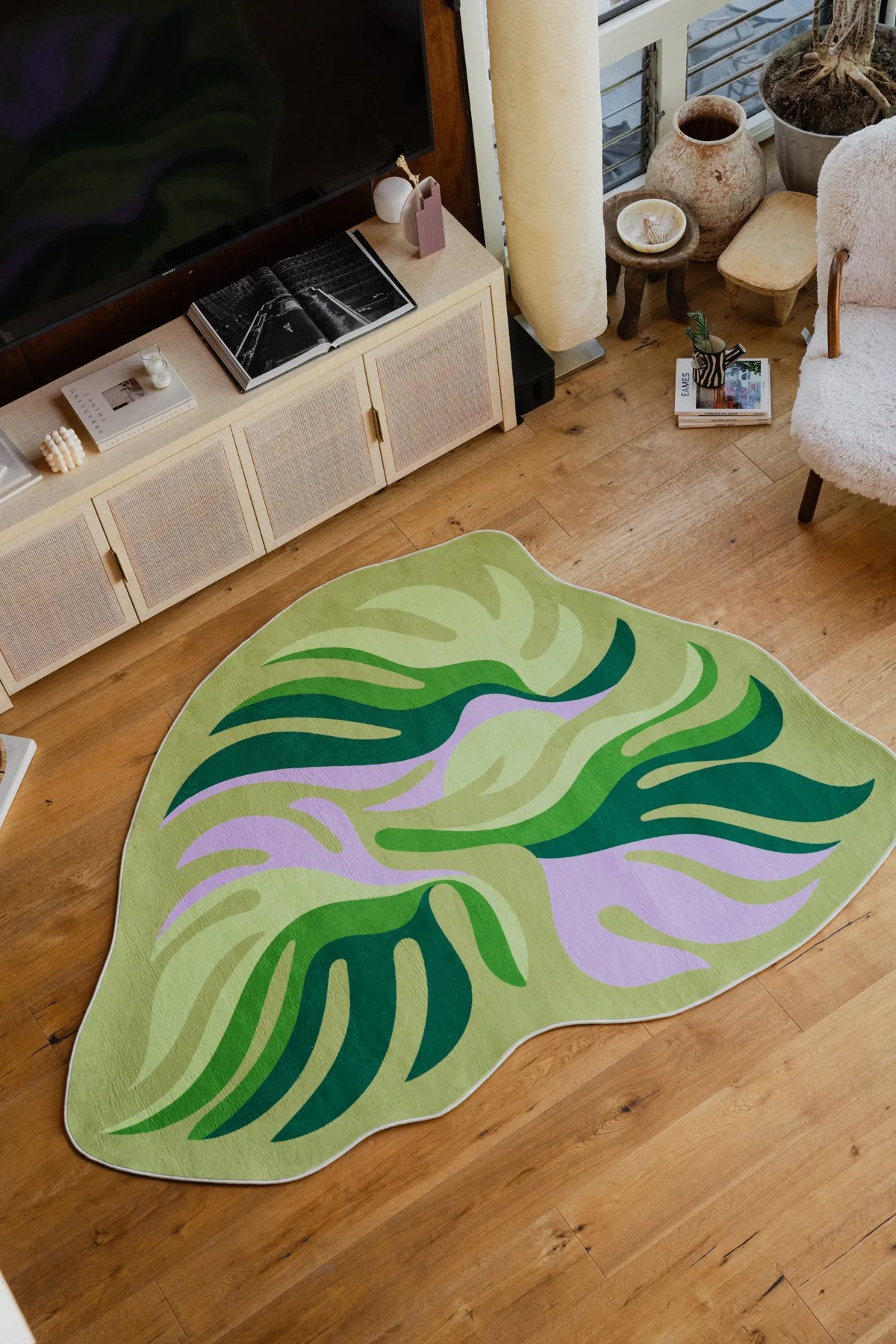 Irregular Botanical Leaves Rug by Maggie Stephenson in the living room, styled with rattan cabinet and boucle armchair.