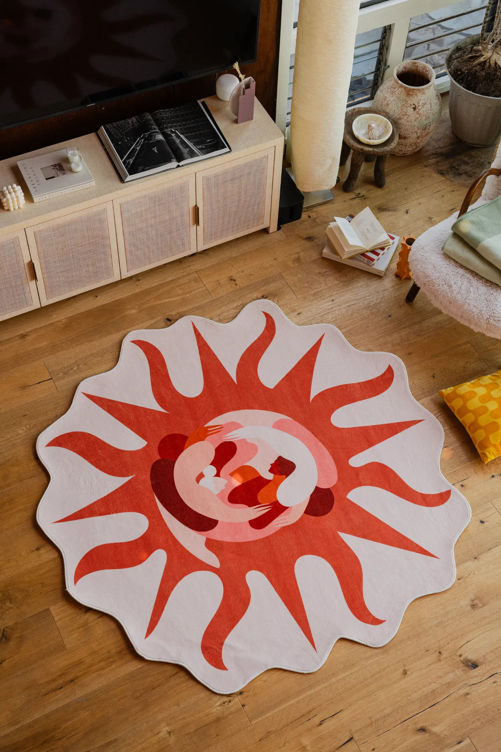 Irregular Solstice Earth Rug placed in front of a TV console and armchair, styled with books and ceramics.