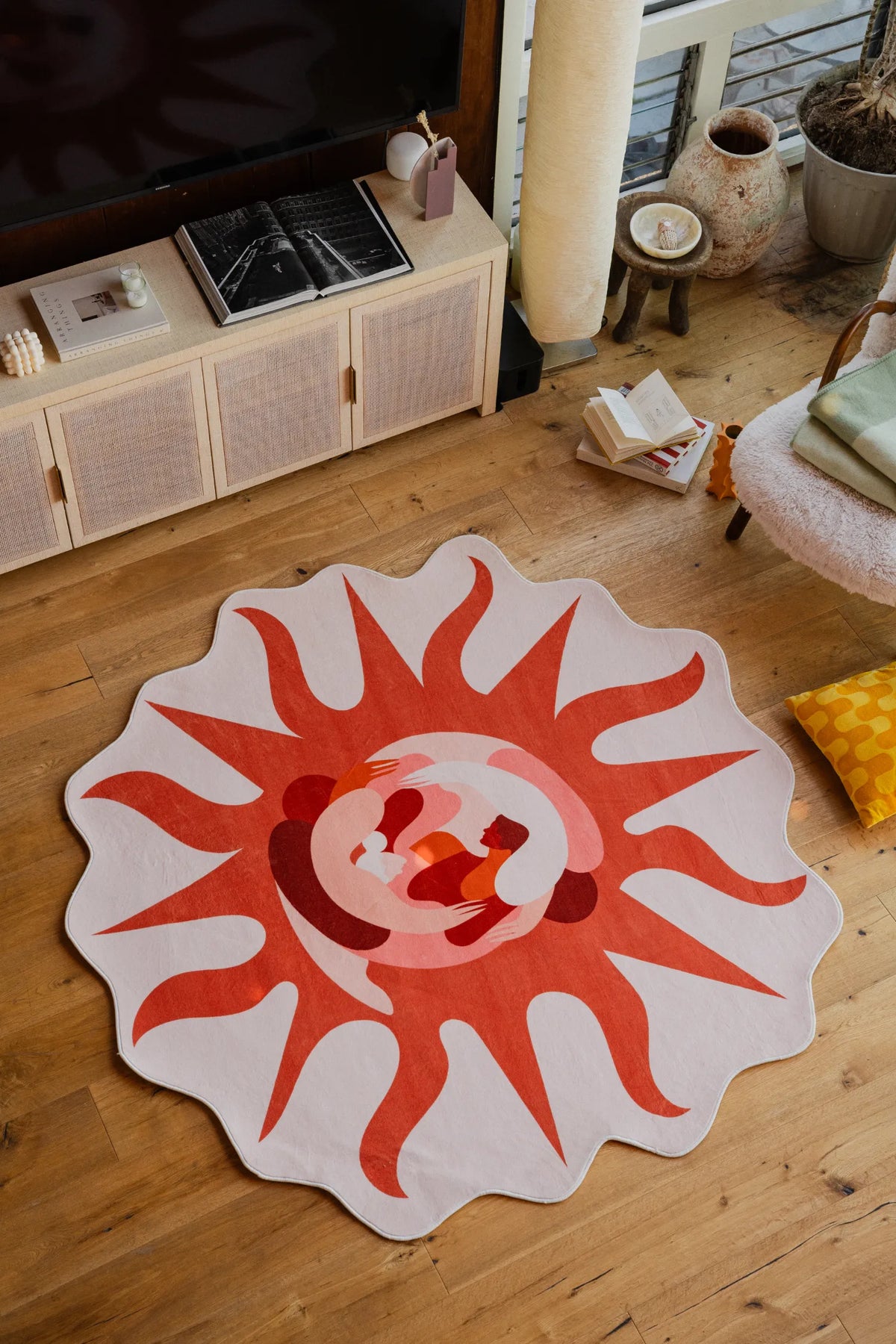 Irregular Solstice Earth Rug placed in front of a TV console and armchair, styled with books and ceramics.