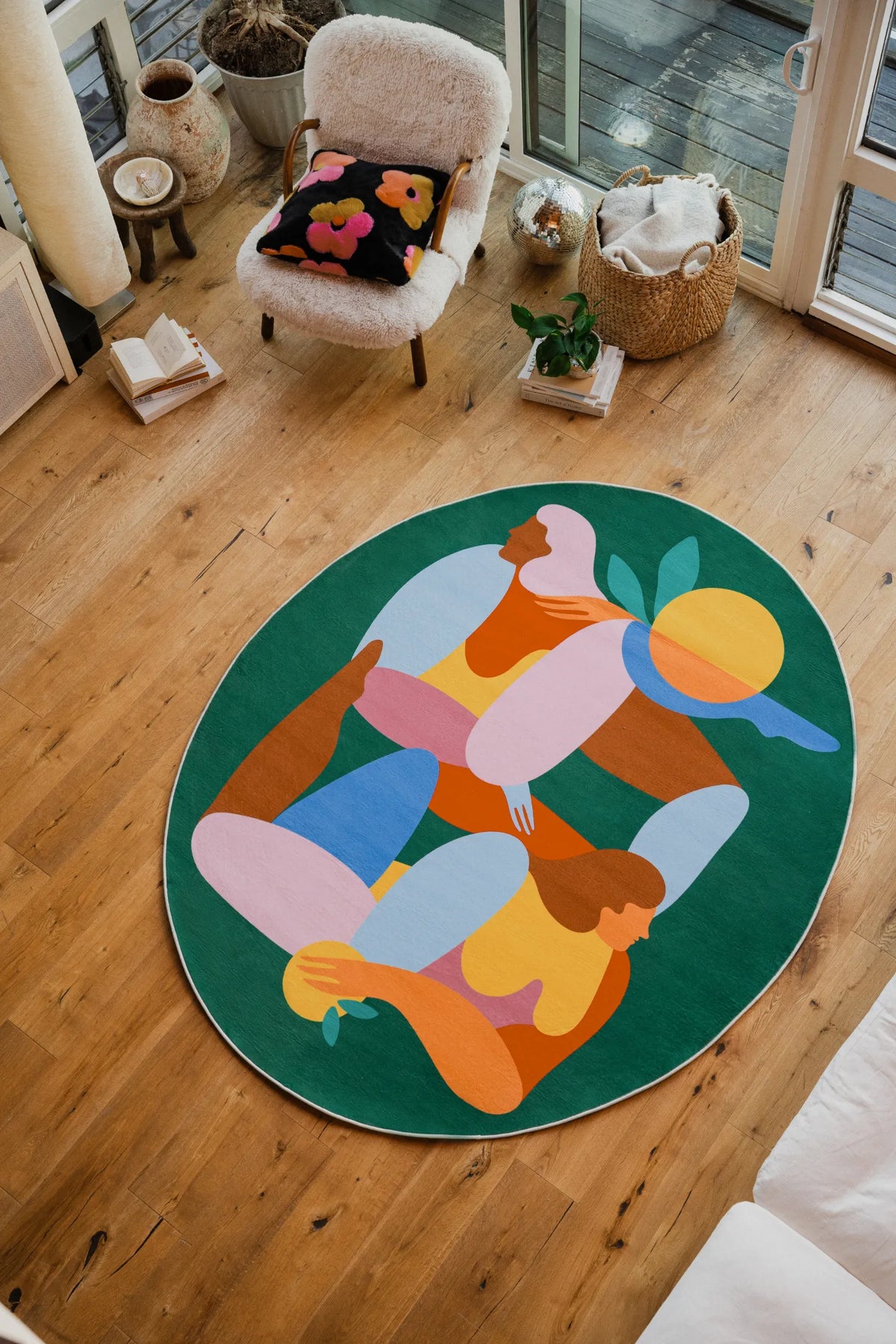 Oval Fruitvine Green Rug by Maggie Stephenson styled in a bright living room with boucle chair and window view.
