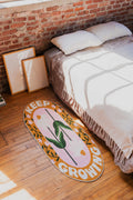 Retro Daisy Quote Rug – “Keep Growing” Oval Rug by Megan Roy on wood floor beside a bed