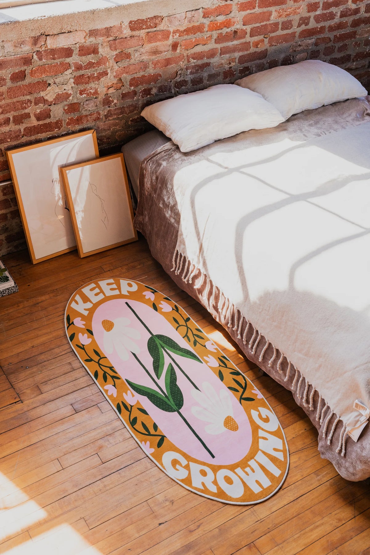 Retro Daisy Quote Rug – “Keep Growing” Oval Rug by Megan Roy on wood floor beside a bed