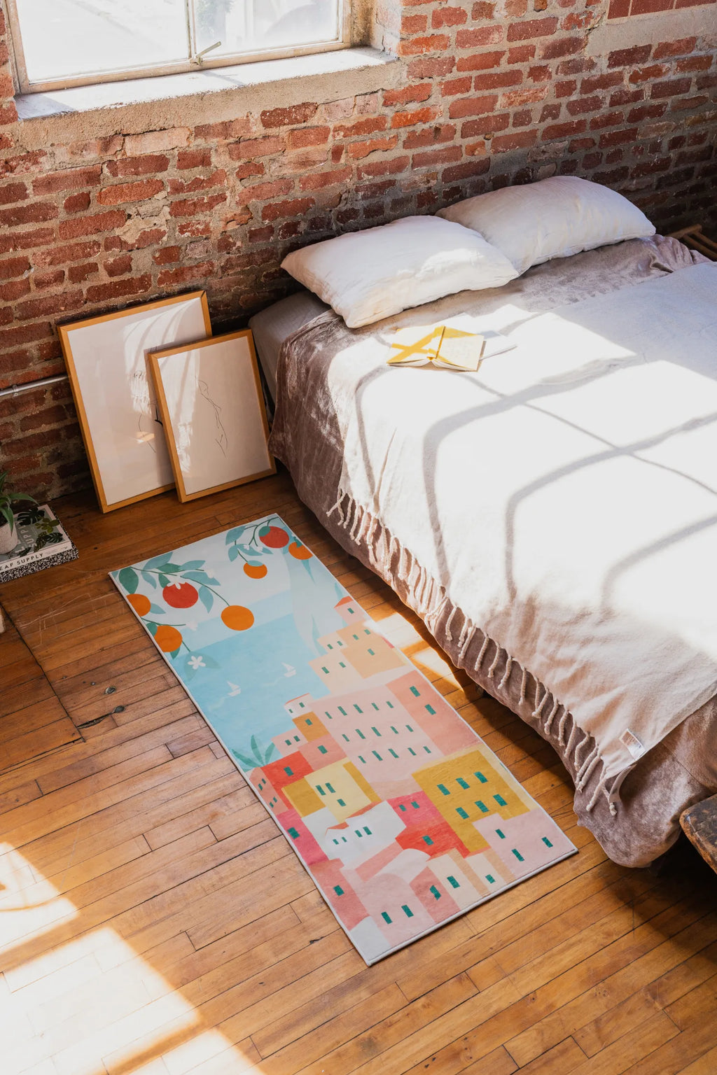 Colorful Italian Village Runner by Petra Lizde on wood floor beside a low bed and brick wall