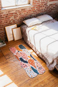 Mosaic Flow Abstract Runner by Jonny Li placed on wood floor beside a low bed under natural light