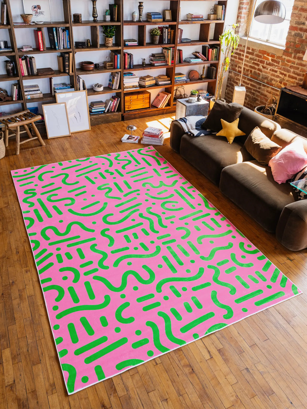 Pink and Green Retro Graphic Area Rug by Shayla Goethe in 7'X10', laid across wood floor beside a modern sofa.
