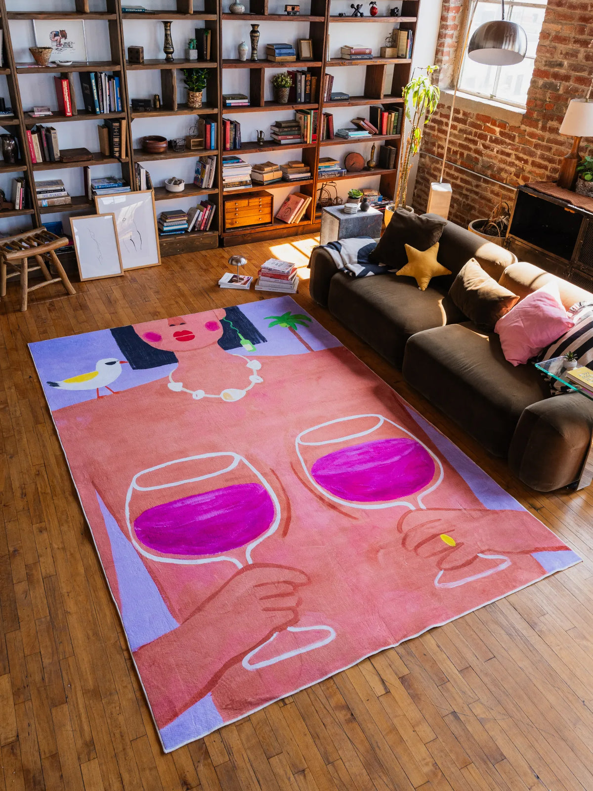 Funky Wine and Woman Art Rug by Nimei, large 7'X10' piece spread across living room floor, styled with sofa, bookshelf and warm light.