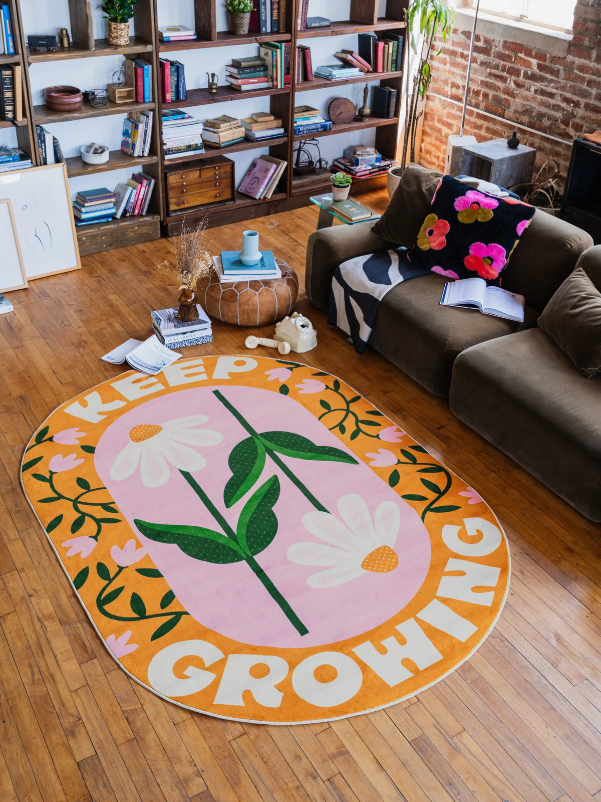 Playful rug with daisy quote design spread across warm wood floor in the living room beside a cozy sofa and bookshelves